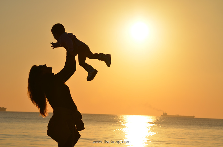 夕阳下海边母子剪影