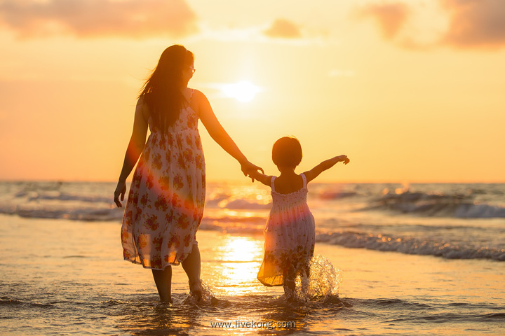 夕阳下海边母女手牵手