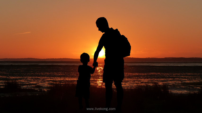 父亲和孩子一起在海边看日出