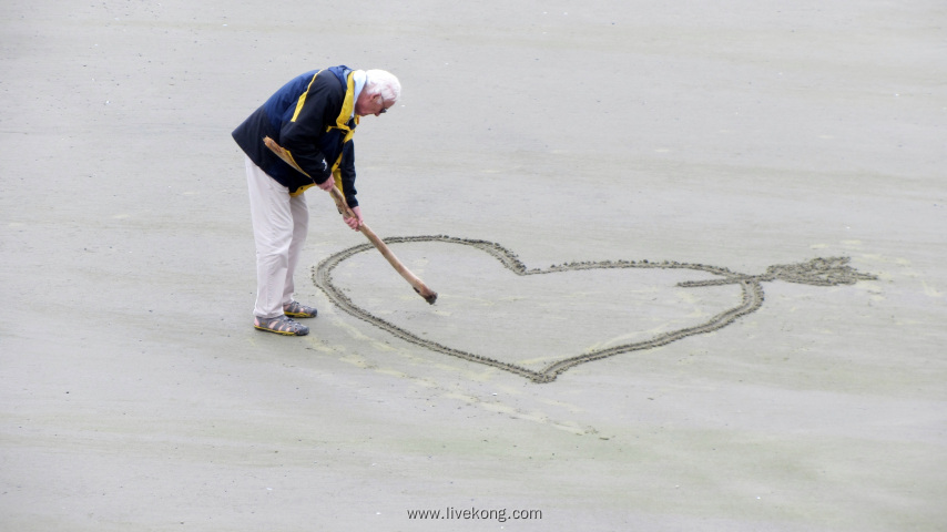 老人在沙地上画爱心