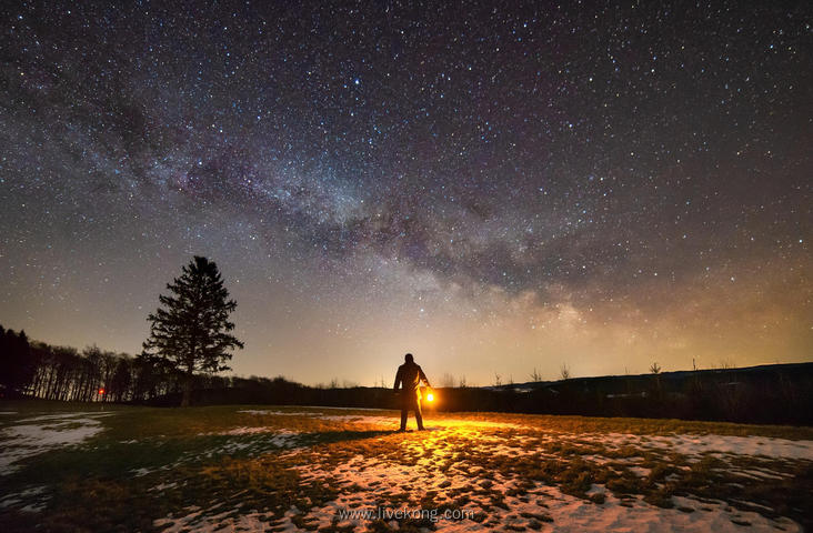 男人提着灯笼站在郊外看星空美景